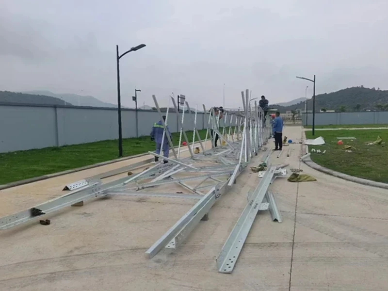 Workers assembling galvanized steel tower sections on the ground
