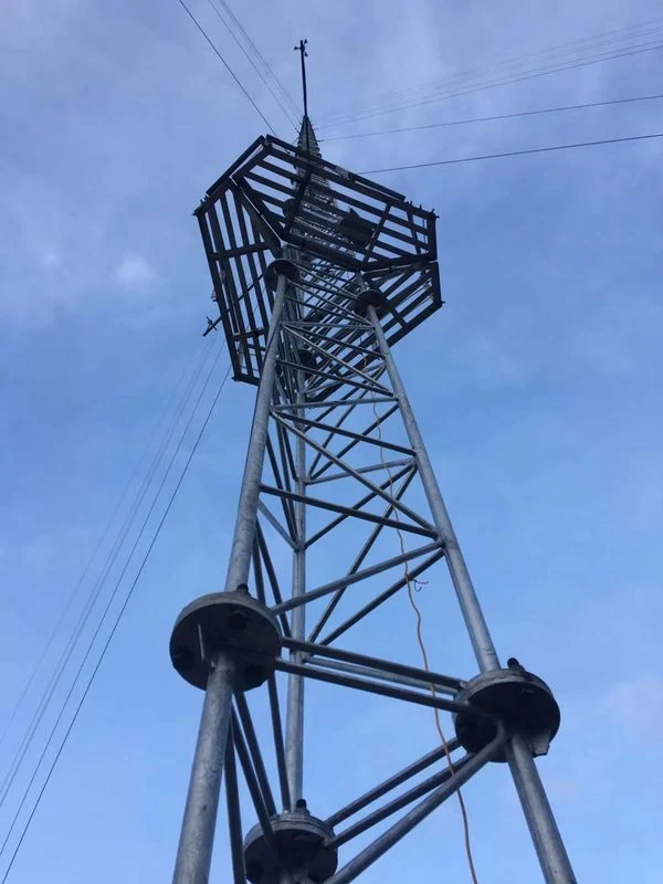 Low-angle view of a galvanized guyed meteorological mast with a square top service platform
