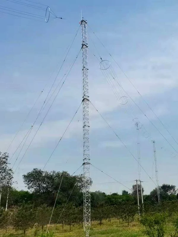 Tall guyed meteorological tower with guy wire array on open rural ground