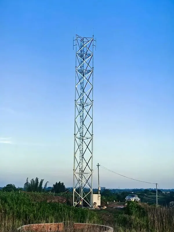Straight-leg square lattice communication tower carrying sector antennas above a rural field