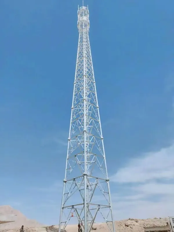 Tall galvanized communication tower with tapered four-leg lattice frame at a desert site
