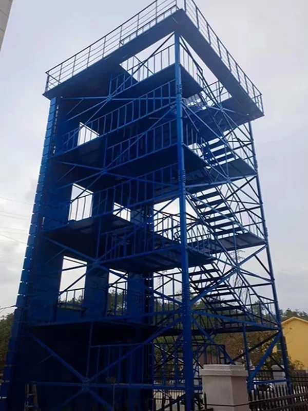 Blue open-frame fire training tower with multi-level drill platforms and external zigzag steel stairs