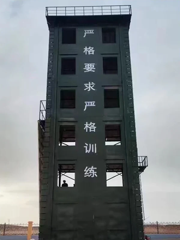 Dark green enclosed fire training tower with multiple window openings, roof guardrail and external access platform