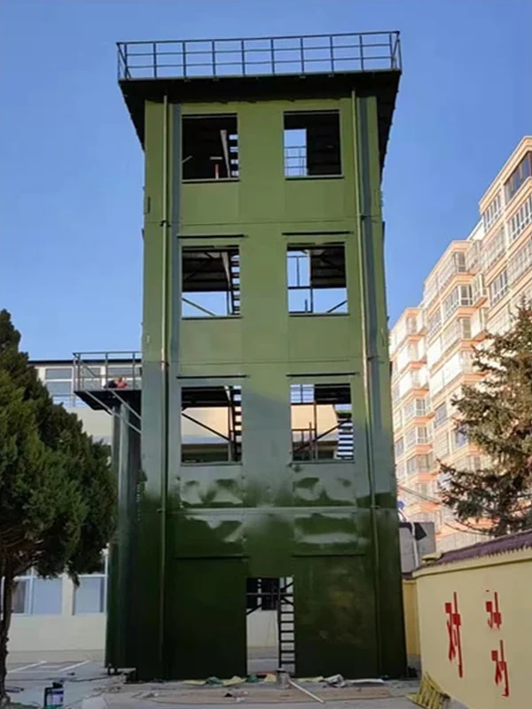 Green modular fire training tower with window openings, side working platform and rooftop guardrail