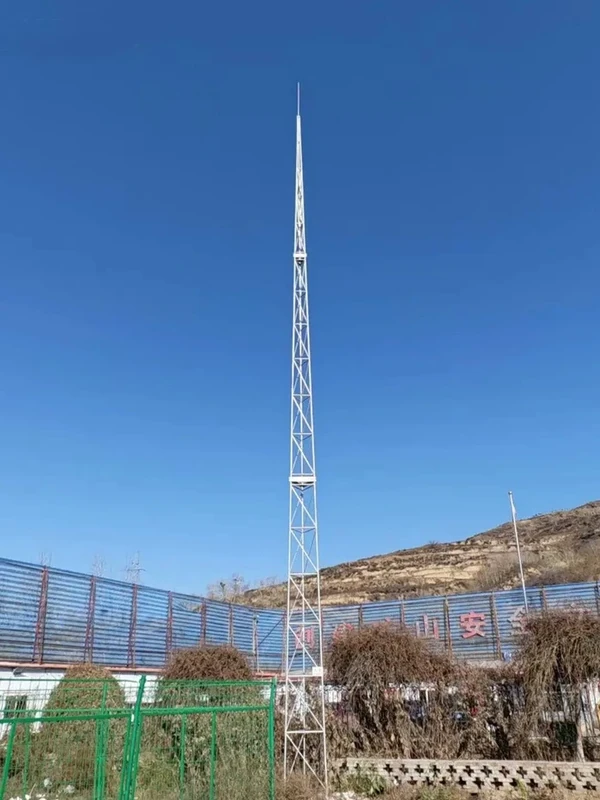 Lattice lightning tower inside a fenced equipment site