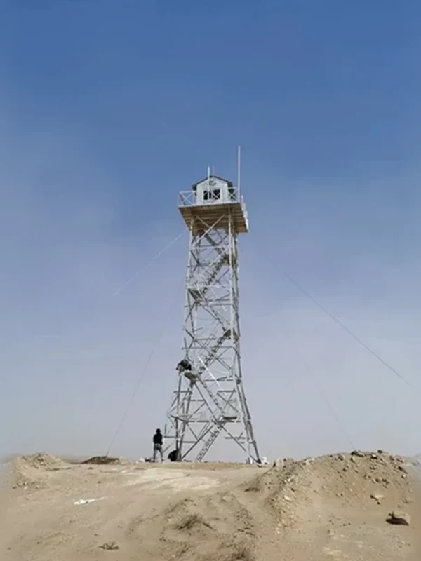 Guyed lattice monitoring tower with square top platform installed at a dry open construction site