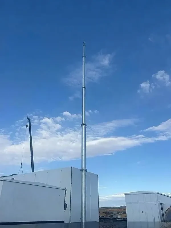 Tubular steel monopole lightning mast beside an industrial building