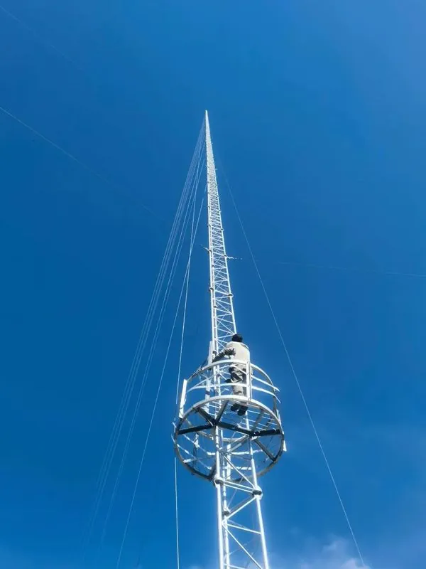 Technician working from a service platform on a lattice wind measurement tower